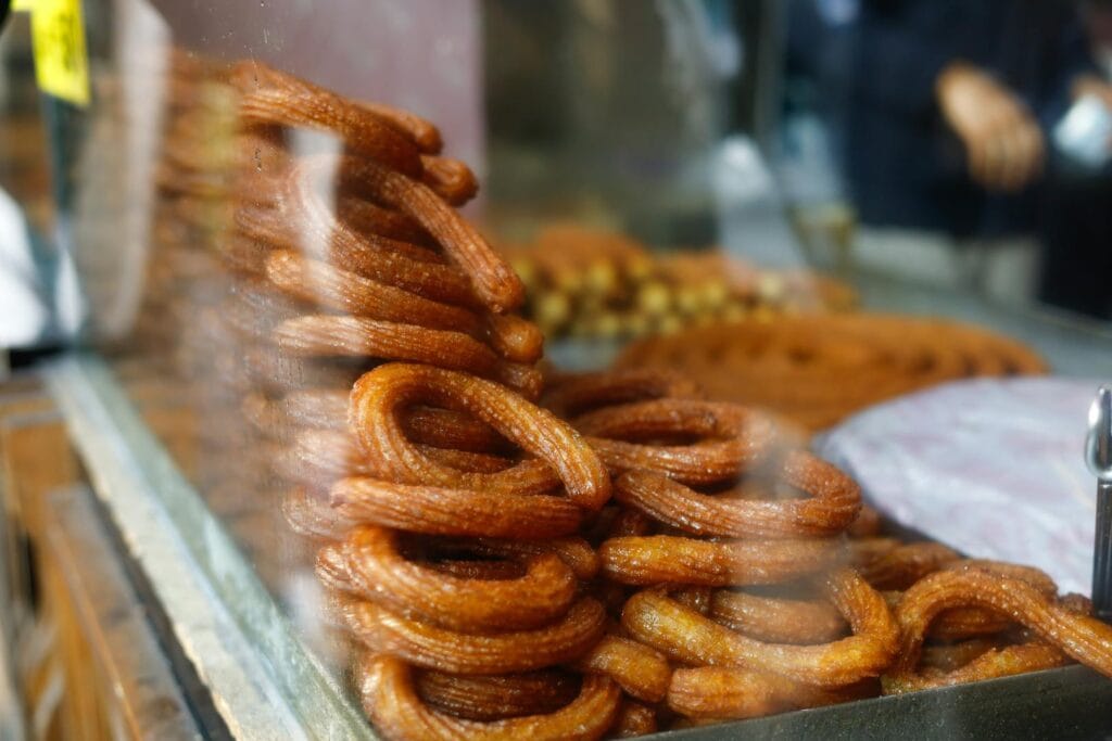 Golden churros stacked at a street food stall, showcasing festive treats.