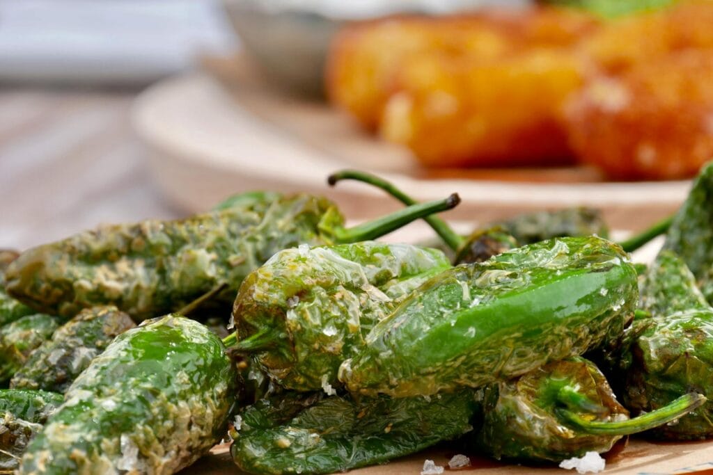 Delicious close-up of roasted Padrón peppers sprinkled with salt, a classic Spanish tapa.