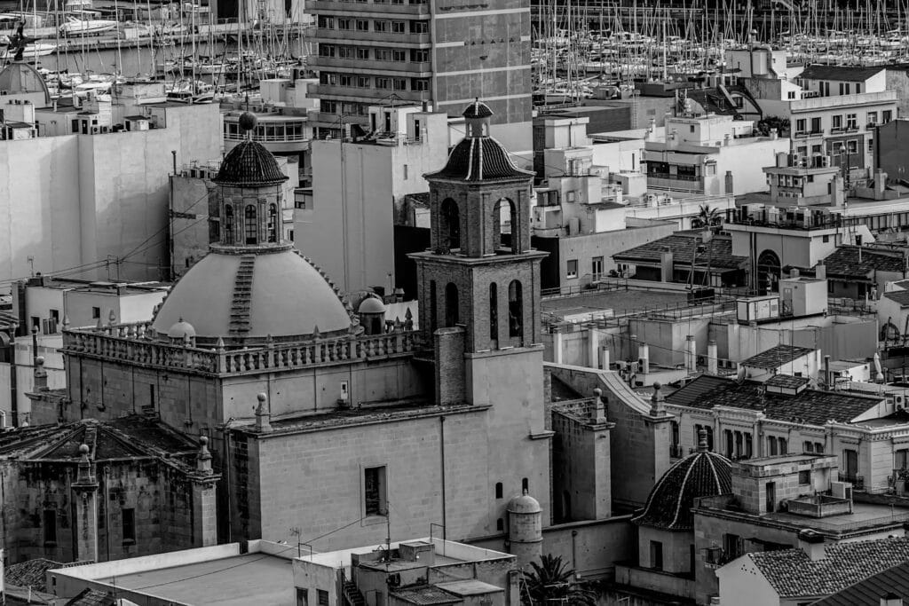 Aerial black and white view of Alicante's urban landscape featuring a historic church.